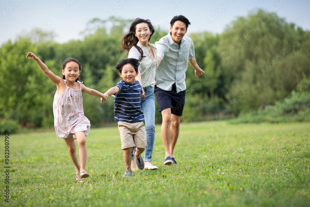 Happy young Chinese family running on grass Happy young Chinese family running on grass