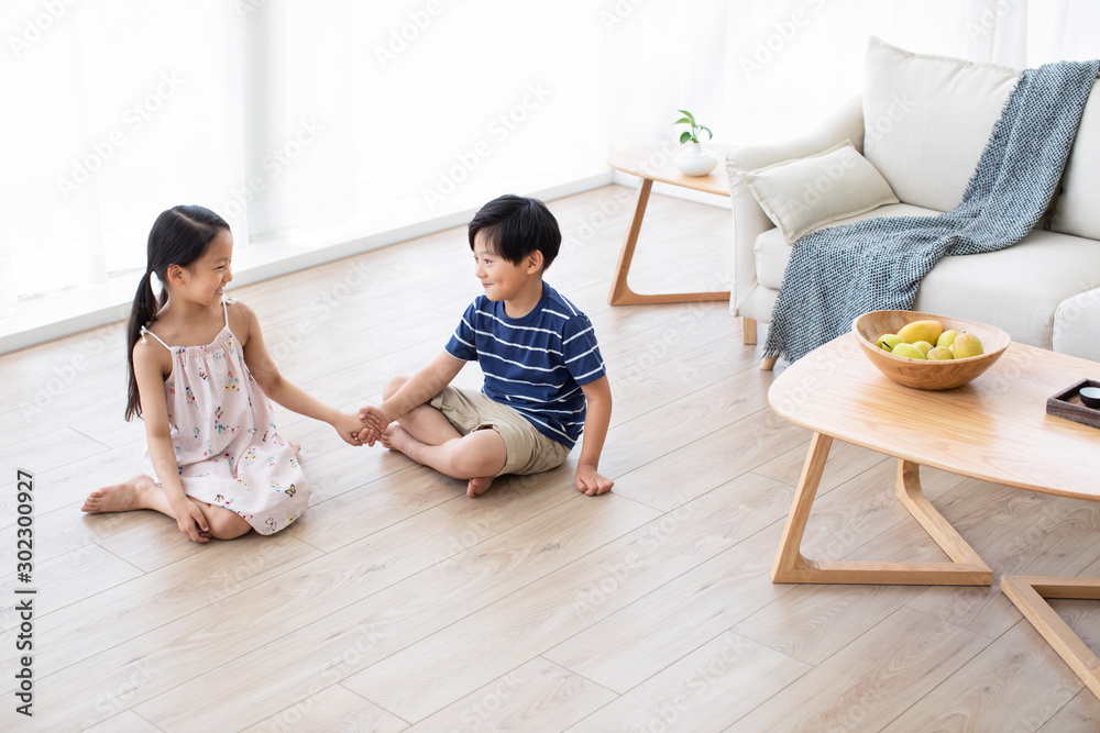 Happy Chinese sibling holding hands in living room