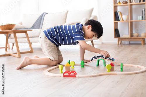 Little Chinese boy playing with toy train on floor photo