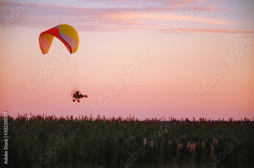 A man flies a paraglider at sunset outside the city in the mountains