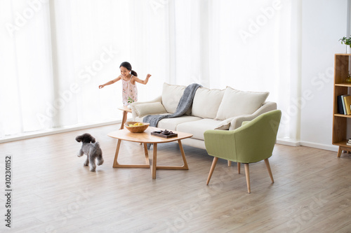 Little Chinese girl playing with dog in living room