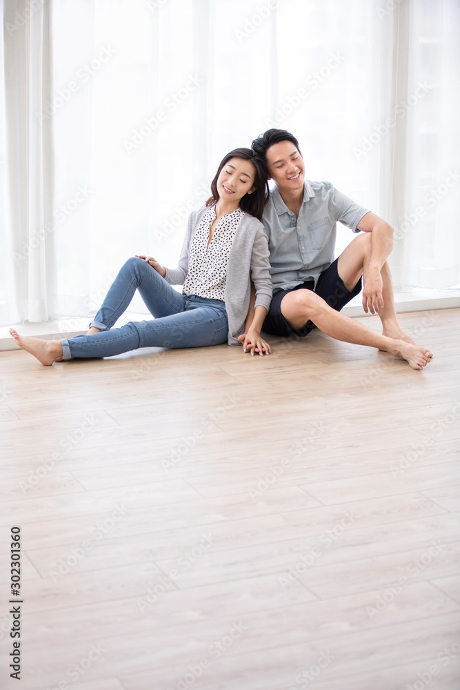 Happy young Chinese couple sitting on floor Happy young Chinese couple sitting on floor