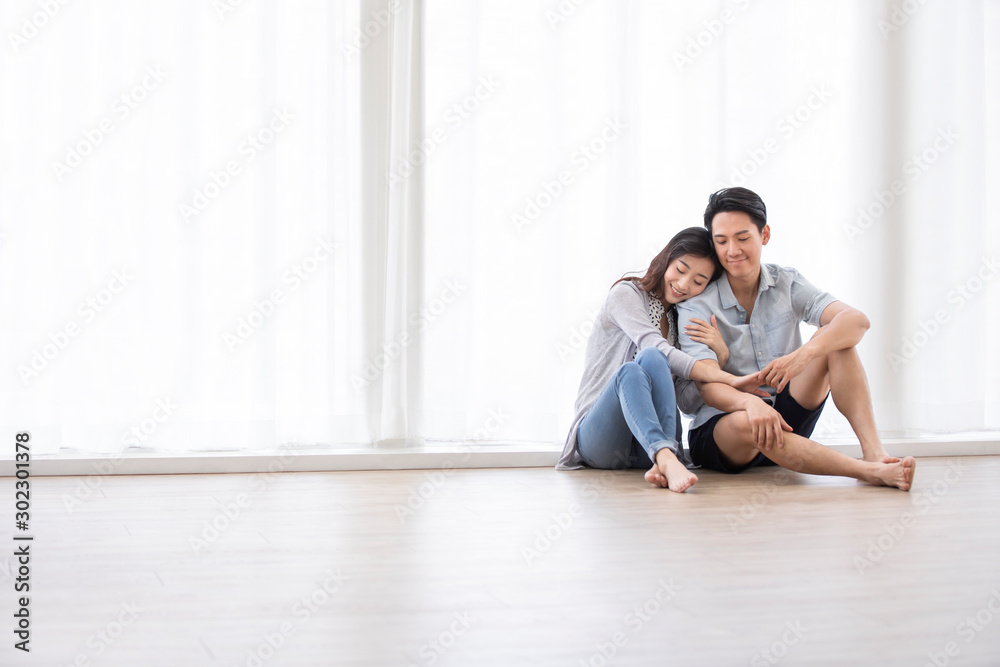 Happy young Chinese couple sitting on floor Happy young Chinese couple sitting on floor
