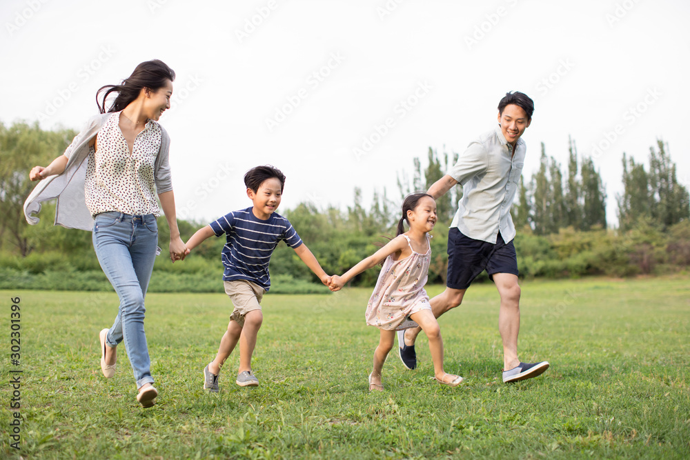 Happy young Chinese family running on grass Happy young Chinese family running on grass