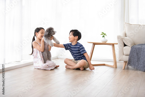 Happy Chinese sibling playing with dog in living room
