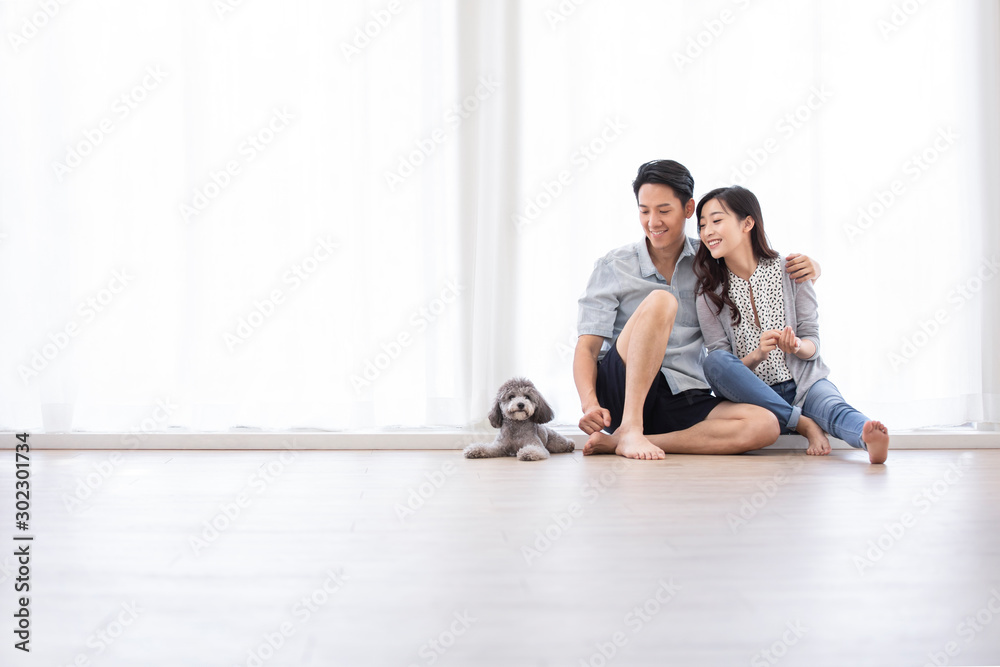 Happy young Chinese couple playing with dog in living room Happy young Chinese couple playing with dog in living room