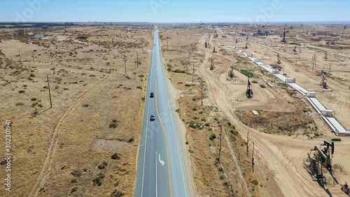 Aerial view of Oil Pumpjack and highway road. Oil industry equipment. Daylight, morning, blue sky. California. USA