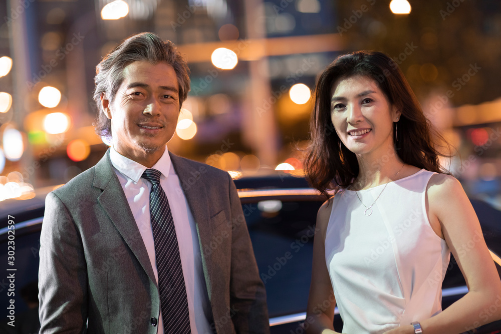 Successful Chinese business people standing near to a car Successful Chinese business people standing near to a car