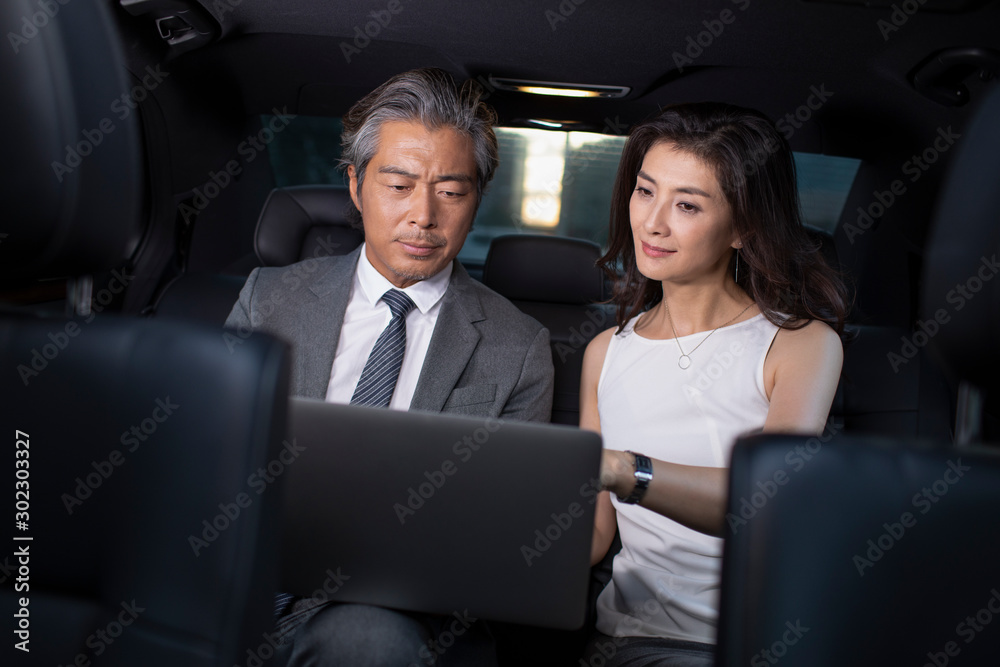 Successful Chinese business people using laptop in a car Successful Chinese business people using laptop in a car
