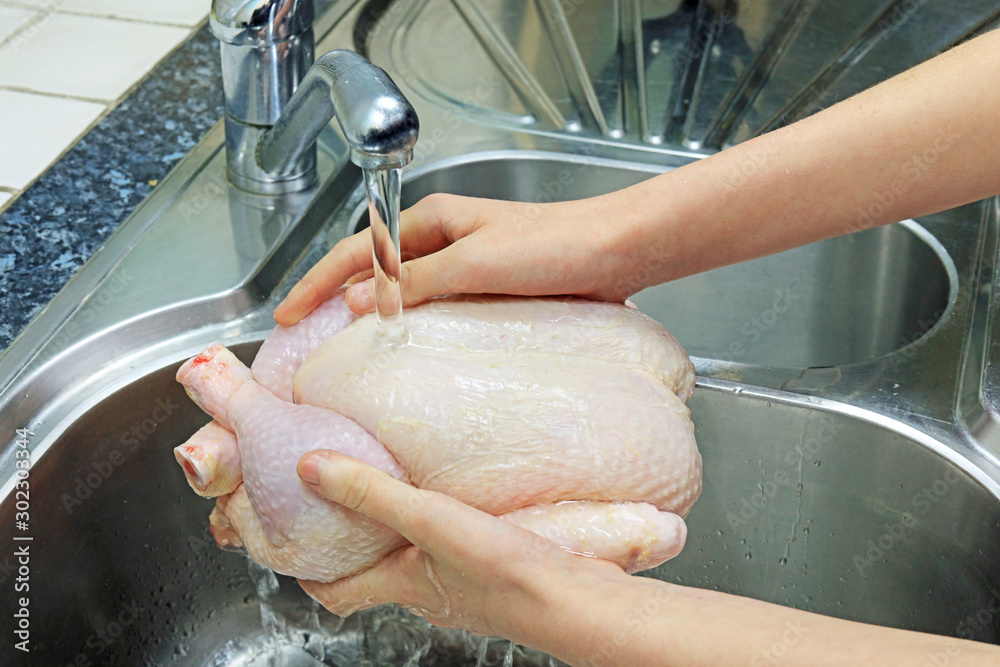 Washing A Fresh Raw Chicken Under Tap Water In The Kitchen Sink. Stock