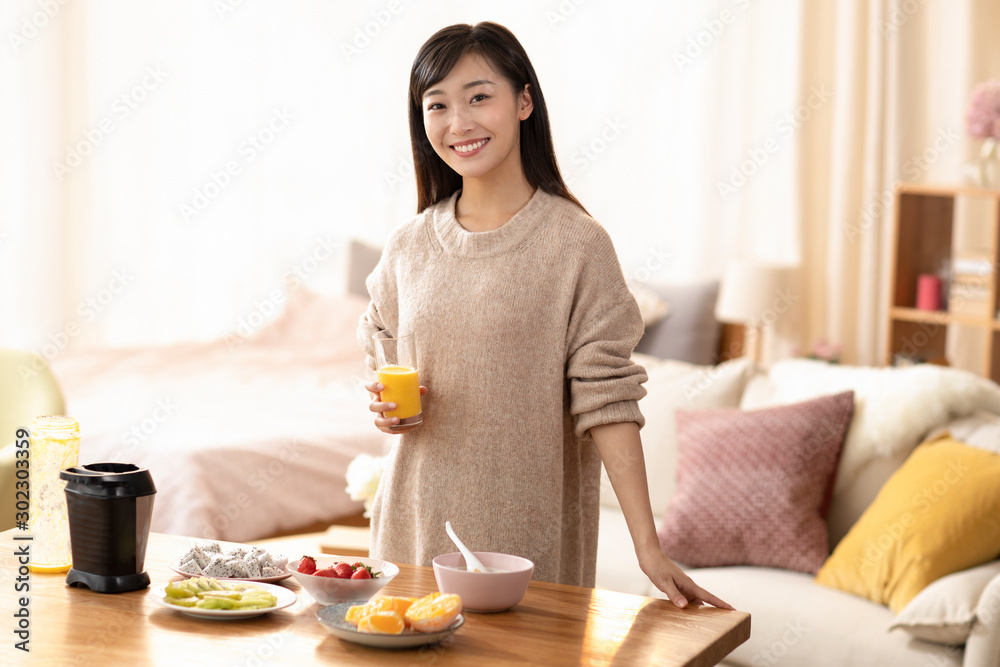 Young Chinese woman making juice at home Young Chinese woman making juice at home