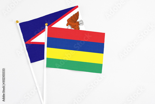 Mauritius and American Samoa stick flags on white background. High quality fabric, miniature national flag. Peaceful global concept.White floor for copy space.