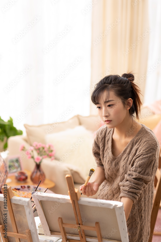 Young Chinese woman painting at home Young Chinese woman painting at home