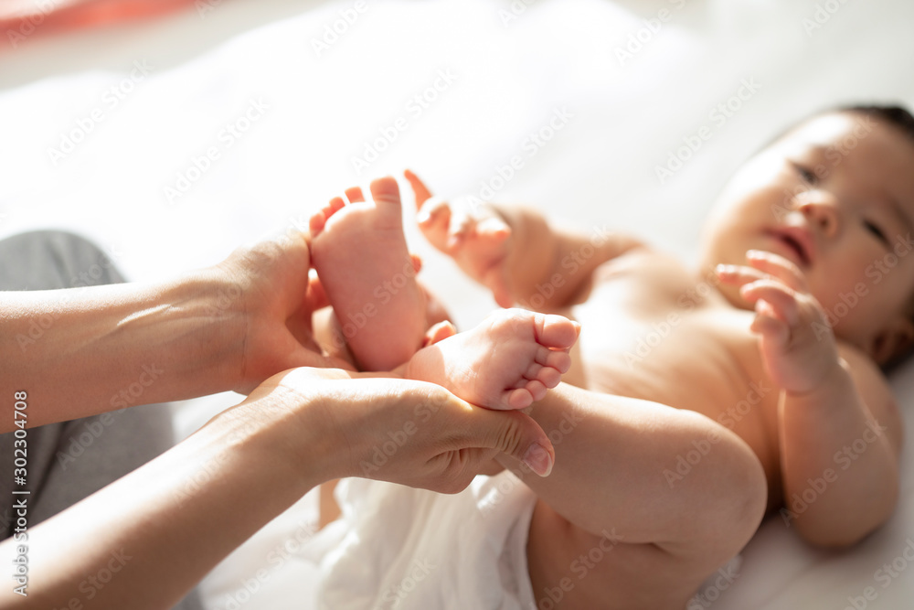 Close-up of young Chinese mom holding baby feet Close-up of young Chinese mom holding baby feet