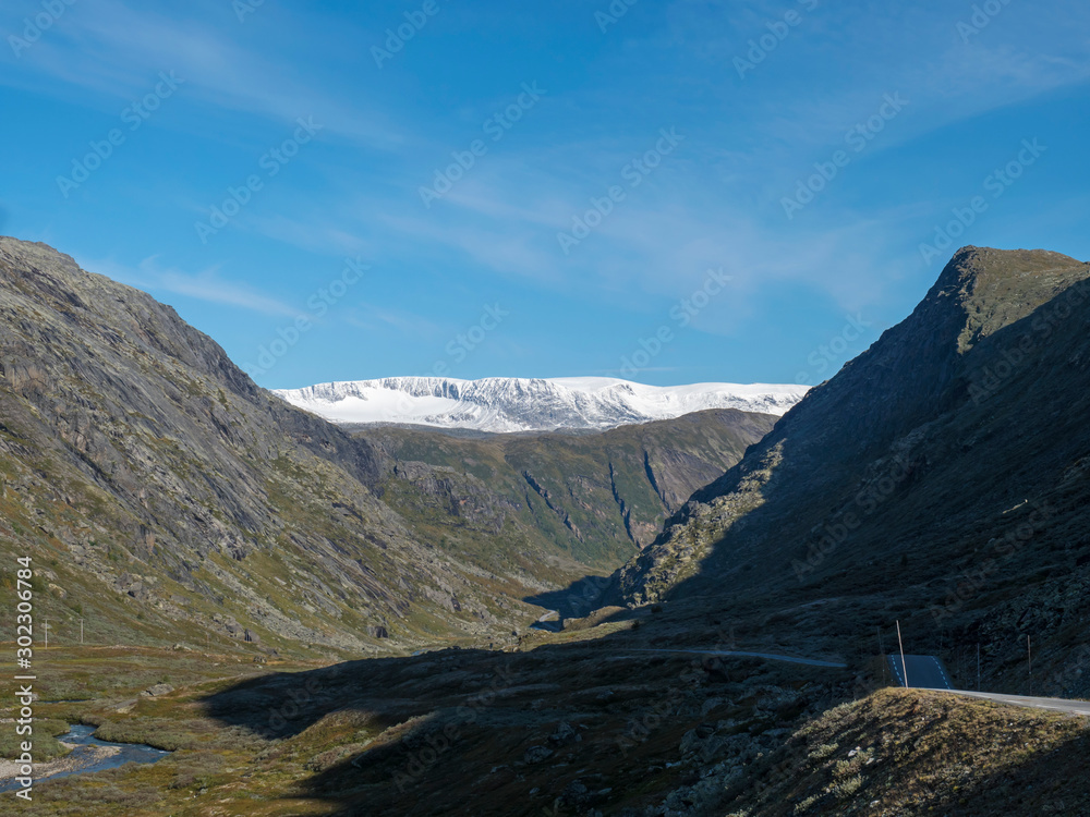Leirdalen Valley with snow capped mountain peaks, forests, wild river stream and road 55 scenic route,Norway. .Nature in the Jotunheimen National park, Norway. Blue sky background