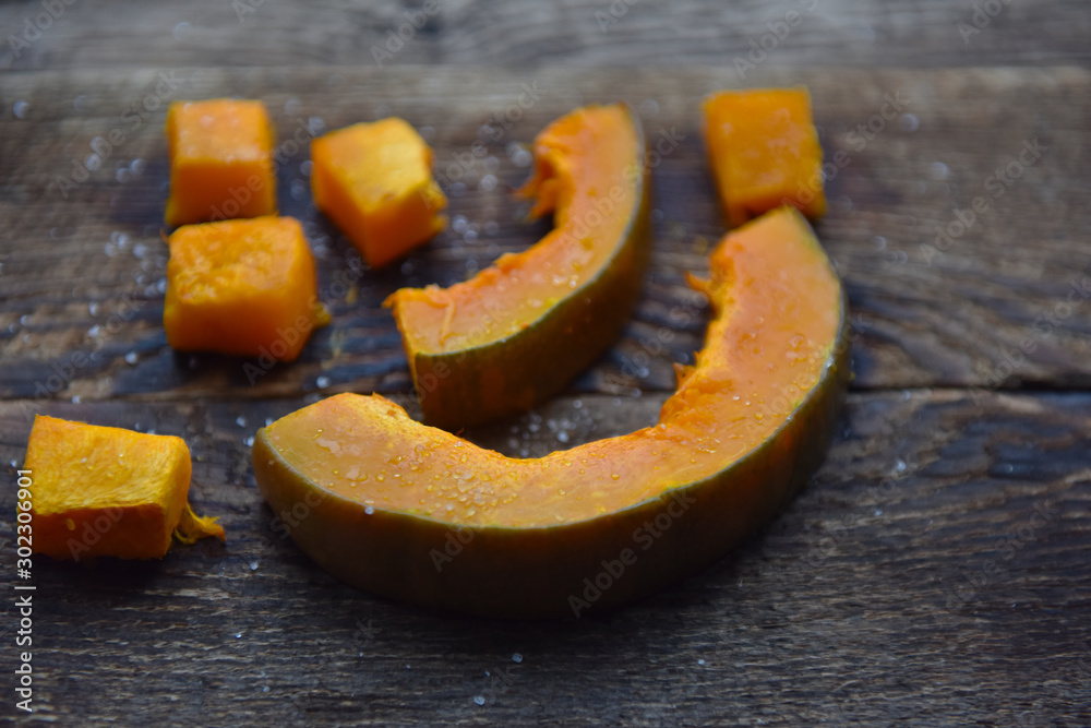 baked orange pumpkin sliced on a wooden table baked orange pumpkin sliced on a wooden table