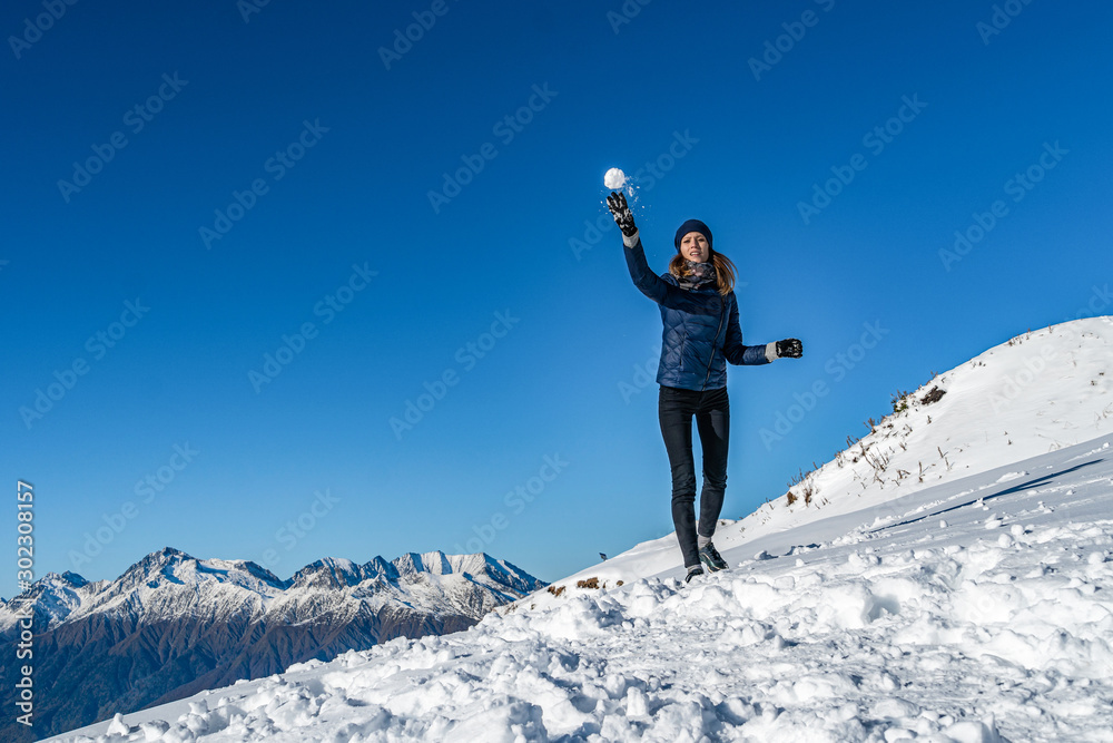 Happy young girl playing snowball fight on the winter snow day