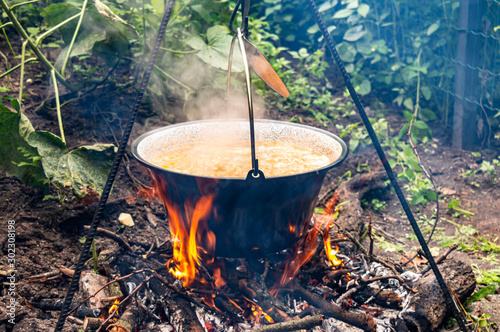 Cooking traditional Hungarian goulash soup in a cauldron outdoors