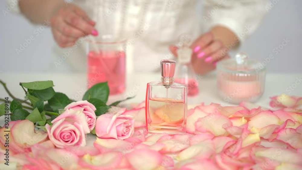 Making body care production beauty aroma perfume roses flowers background on table, Hand of female perfumer lab technician chemist cosmetician pouring cosmetic aroma glass test tube oil in liquid, 4 K Making body care production beauty aroma perfume roses flowers background on table, Hand of female perfumer lab technician chemist cosmetician pouring cosmetic aroma glass test tube oil in liquid, 4 K