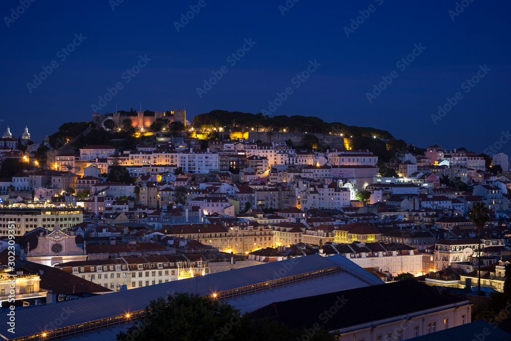 Scenic view of the Sao Jorge Castle (Saint George Castle, Castelo de Sao Jorge) and Alfama district in downtown Lisbon, Portugal at dusk. Viewed from the Miradouro de Sao Pedro de Alcantara viewpoint.
