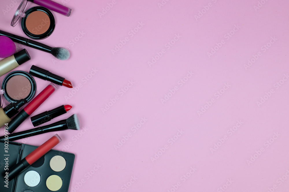 A set of cosmetics for make up of lipsticks, lip glosses, creams foundation, blush, powder, highlighter and eye shadow lies on a pink background. top view. copy space. horizontal A set of cosmetics for make up of lipsticks, lip glosses, creams foundation, blush, powder, highlighter and eye shadow lies on a pink background. top view. copy space. horizontal