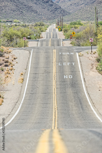 Rural highway at dusty field with power line and remote mountain range in Tucson, Arizona, USA