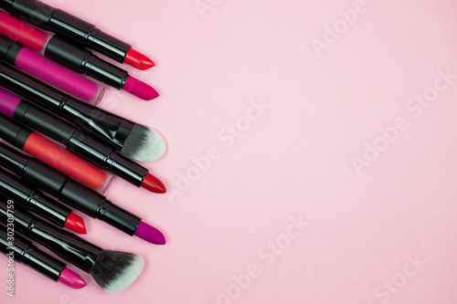 A set of cosmetics for make up, consisting of lipsticks, lip glosses lies on a pink background. top view. copy space. horizontal