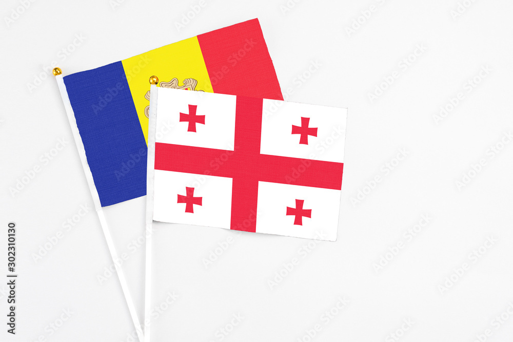 Georgia and Andorra stick flags on white background. High quality fabric, miniature national flag. Peaceful global concept.White floor for copy space.