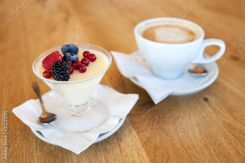 Panna cotta with fresh berries and cappuccino on the table in  cafe