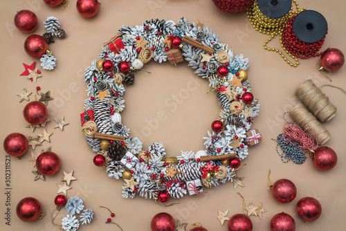top view of handmade Christmas wreath with cones and red toys and decorative berries on craft background