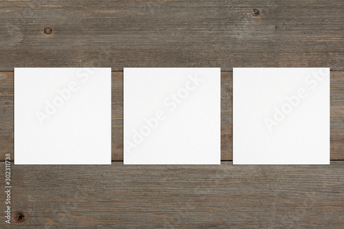 Three empty square white business cards template on wooden background. Flat lay, top view. Open composition. For branding identity, logo design pitches and marketing.