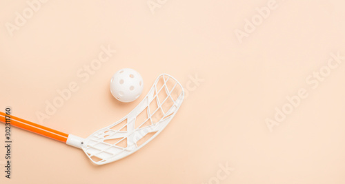 Photography floorball stick and white ball isolated on a light brown background
