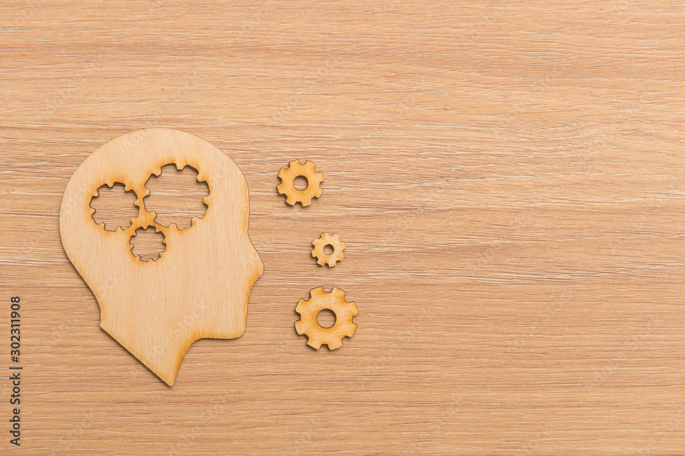 Fototapeta premium Business and design concept - wooden man head silhouette with gear icon on wooden background