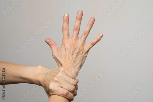 Woman holding wrist tightly isolated on grey background