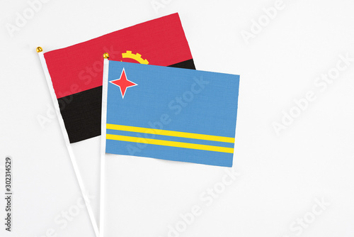 Aruba and Angola stick flags on white background. High quality fabric, miniature national flag. Peaceful global concept.White floor for copy space. photo