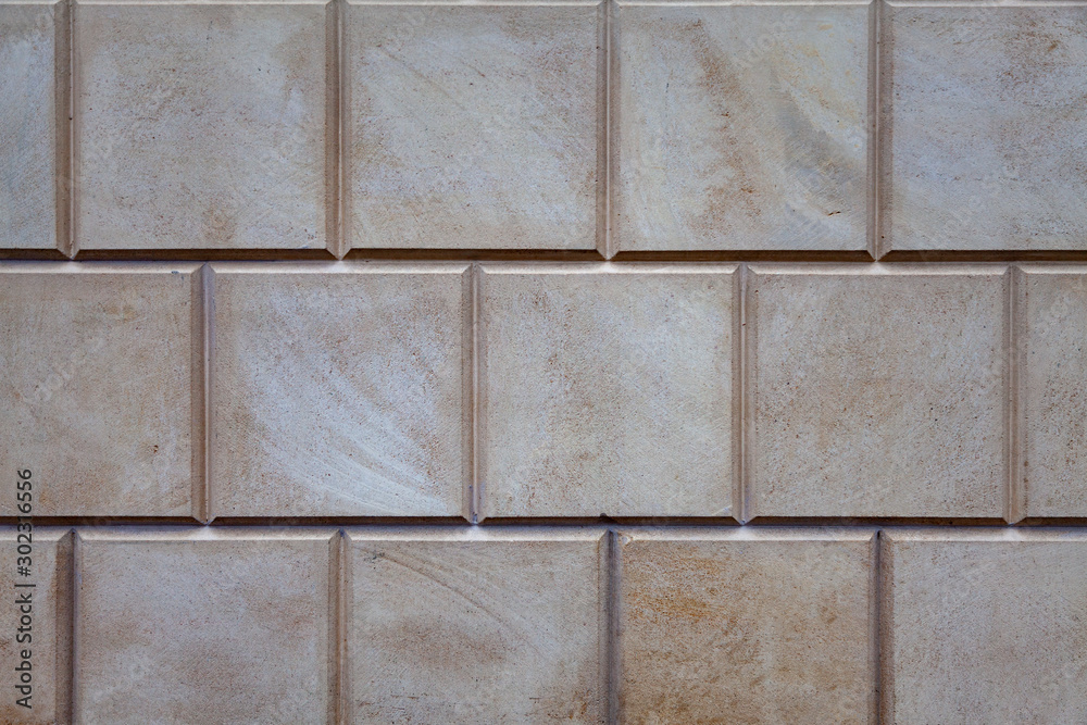 Naklejka premium Texture - wall of the building, lined with square stone tiles of neutral color