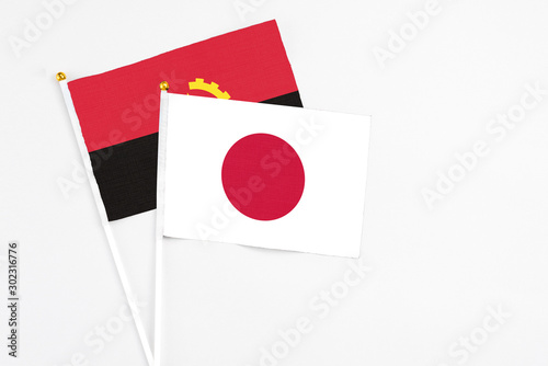 Free Download Japan and Angola stick flags on white background. High quality fabric, miniature national flag. Peaceful global concept.White floor for copy space. - GFXLoad