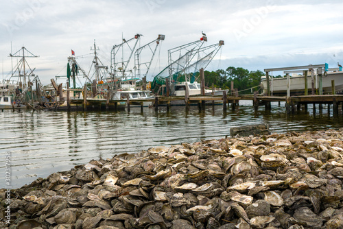 Fishing boats docked in Bon Secour Alabama with piles of oyster shells in foreground