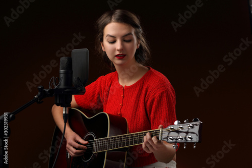 Fotografía Girl with a guitar in front of a Studio microphone
