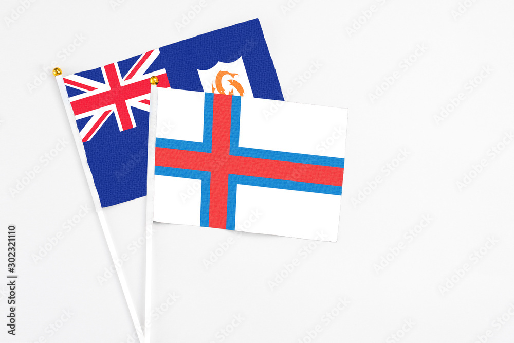 Faroe Islands and Anguilla stick flags on white background. High quality fabric, miniature national flag. Peaceful global concept.White floor for copy space.