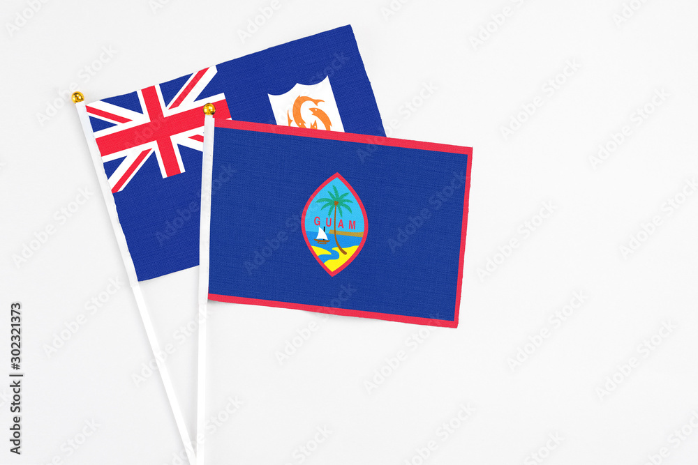 Fototapeta premium Guam and Anguilla stick flags on white background. High quality fabric, miniature national flag. Peaceful global concept.White floor for copy space.