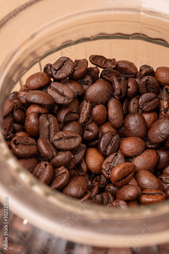 Freshly roasted coffee beans in a glass jar. On a stone background.