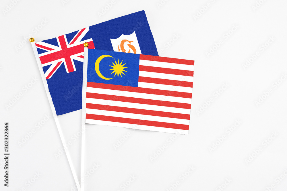 Fototapeta premium Malaysia and Anguilla stick flags on white background. High quality fabric, miniature national flag. Peaceful global concept.White floor for copy space.