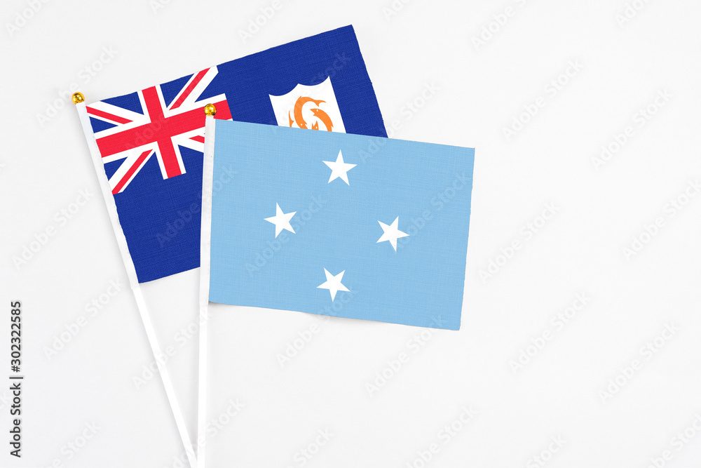 Fototapeta premium Micronesia and Anguilla stick flags on white background. High quality fabric, miniature national flag. Peaceful global concept.White floor for copy space.