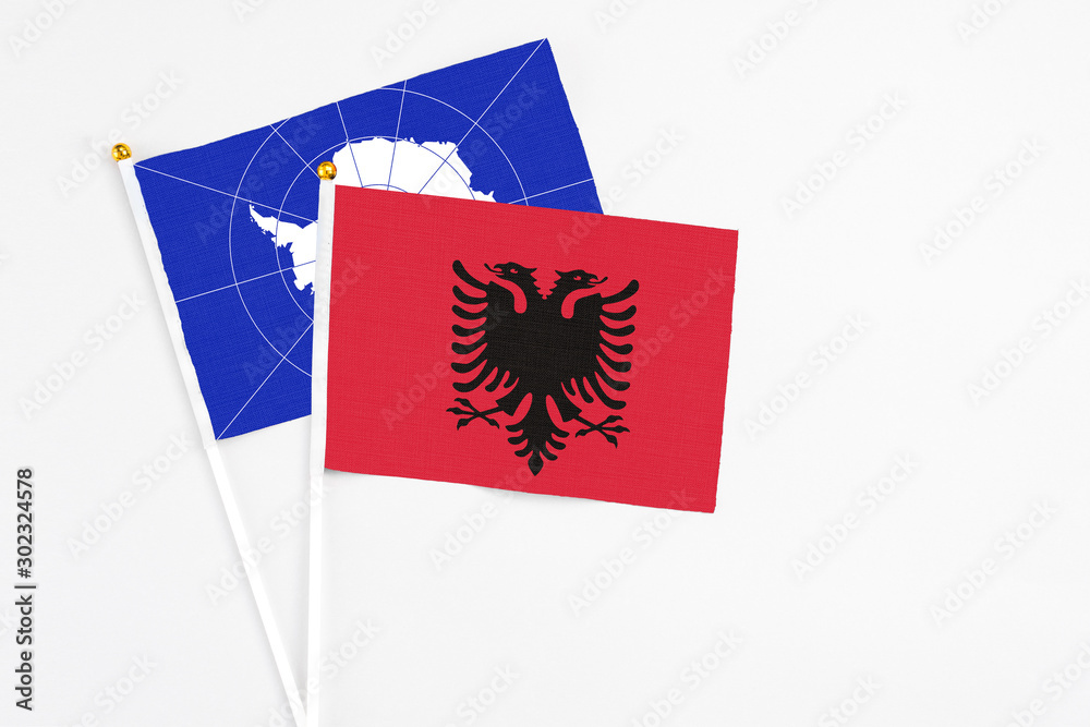 Obraz premium Albania and Antarctica stick flags on white background. High quality fabric, miniature national flag. Peaceful global concept.White floor for copy space.