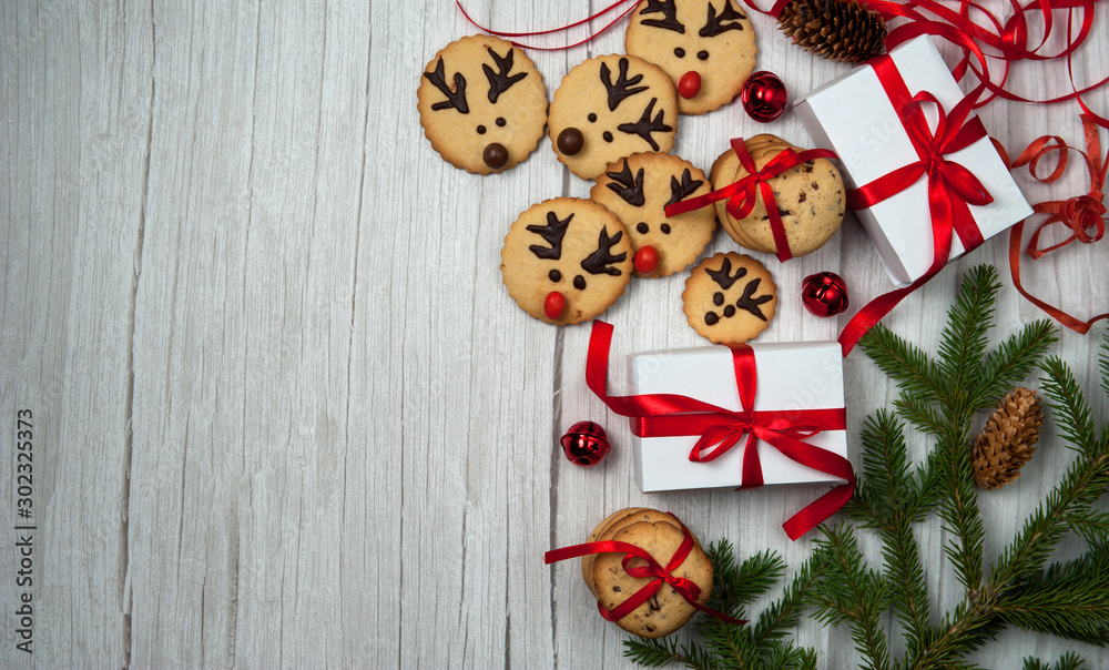 Christmas composition.Gift boxes, homemade gingerbread in the form of Santa's reindeer, fir branches and cones, red ribbons and bells on a light wooden background. Christmas, winter, New year. Christmas composition.Gift boxes, homemade gingerbread in the form of Santa's reindeer, fir branches and cones, red ribbons and bells on a light wooden background. Christmas, winter, New year.