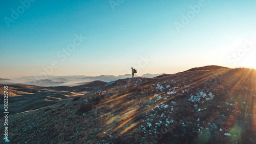 Winner silhouette on the mountain top. Sport and active life concept. Sunset behind.