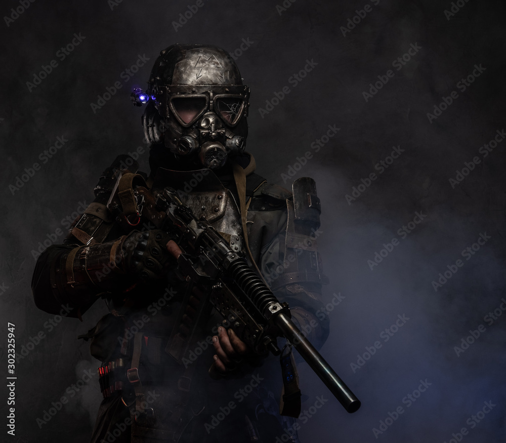 In the mist of smoke at dark studio man in dark apocalypse knight costume is posing for photographer.
