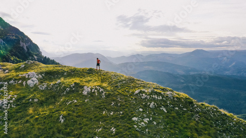 Aerial view of a trail running man standing on the ridge of a mountain