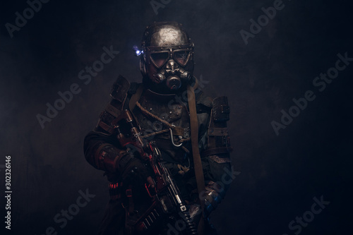 Dark post apocalypse knight is posing for photographer in light smoke.